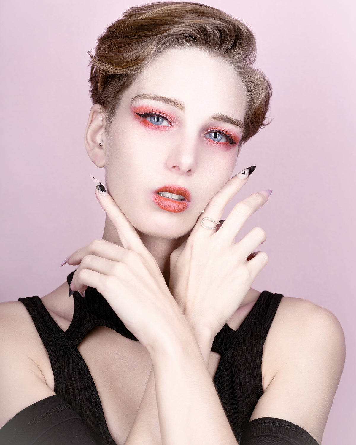 Rosée d’agrumes II par SchaPicShow : portrait sur fond rose poudré, maquillage corail et mains encadrant le visage.