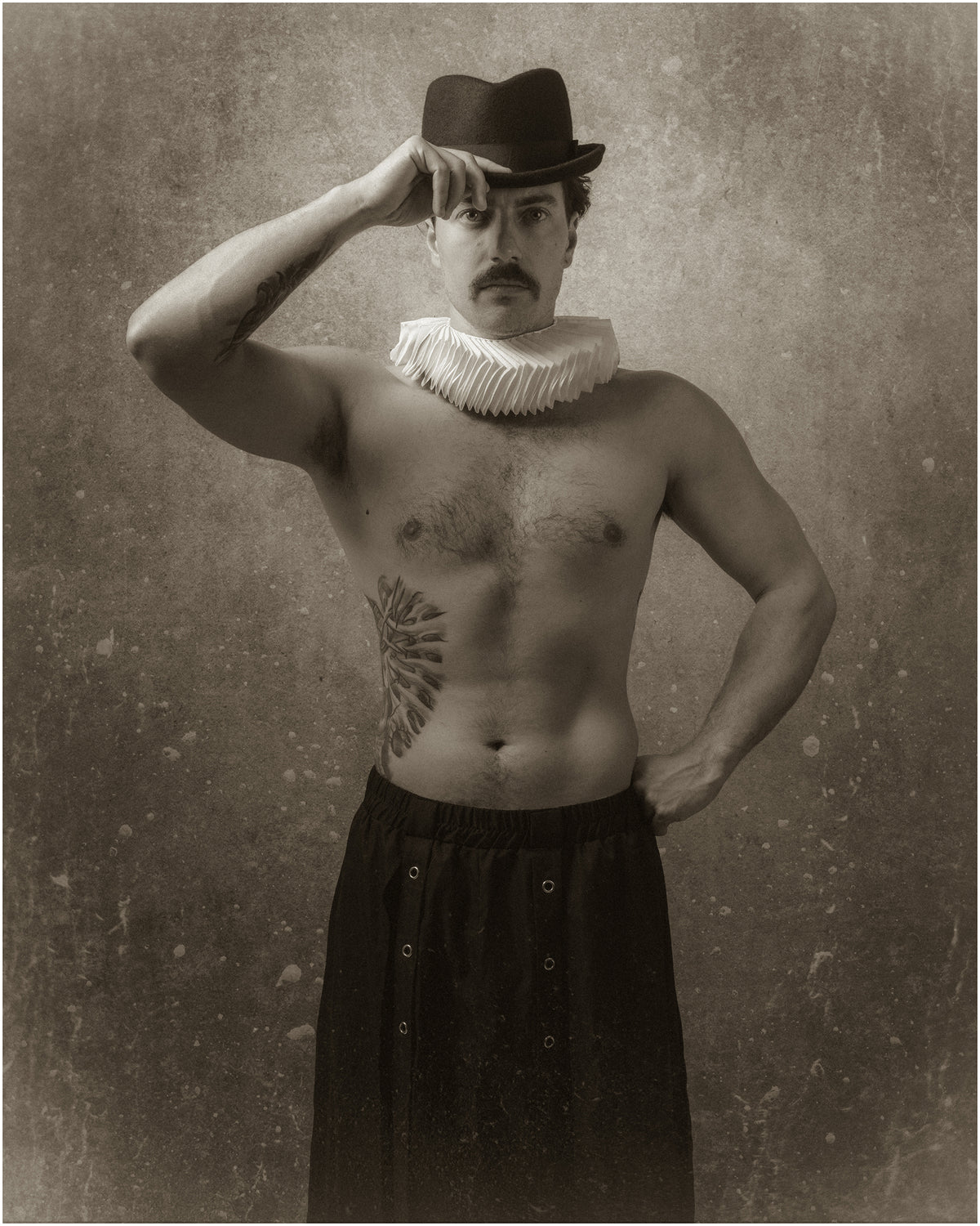 Portrait sépia d’un homme moustachu, torse nu, portant une collerette blanche et un chapeau sombre dont il touche le bord, l’autre main sur la hanche, sur fond vieilli. Portrait Retrouvé 1837 – IIII, par SchaPicShow.